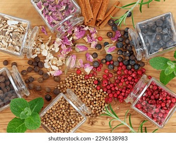 Top view of herbs and botanicals for cocktails or gin flavoring on wooden table with juniper berries, pink peppercorns, allspice, dried rose petals, sweet dried orange peels and cinnamon sticks - Powered by Shutterstock