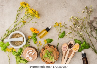 top view of herbs, green leaves, mortar with pestle, bottles and pills in wooden spoons on concrete background, naturopathy concept - Shutterstock ID 1791364367