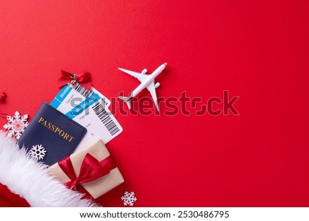 Top view of a holiday travel setup featuring a passport, boarding passes, gift, and airplane over a red background, symbolizing festive travel plans