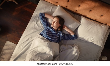 Top View Home: Beautiful Young Woman Sleeps in Her Bed, Sun Shines on Her and She Opens Eyes and Greets New Sunny Day. Joyful Waking Up of a Girl Ready for Productive Day. Top Down Above Shot - Powered by Shutterstock