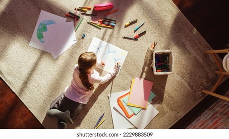 Top View Home: Little Girl Drawing Beautiful Wind Power Turbines Looking Like Flowers. On Sunny Day Smart Child Imagining Planet as a Happy Place with Clean, Sustainable Green Energy for All. - Powered by Shutterstock