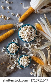 Top view of Home made fresh popped popcorn with unpopped kernels and organic grown dry corn cob against grey background . Copy space 