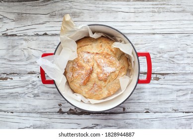 Top View Of Homemade Artisan Bread Freshly Baked In A Red Dutch Oven. Flatlay.