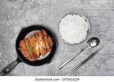 Top View Homemade Breaded Fried Chicken Chop Topped Spring Onion On The Mini Black Pan  And A Bowl Of Steamed Rice