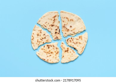 Top view with a homemade naan bread split into more pieces. Delicious Indian flatbread minimalist on a blue background - Shutterstock ID 2178917095