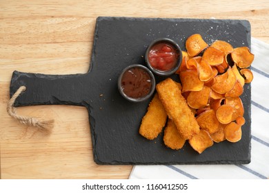 Top View Homemade Organic Baked Fried Sweet Potatoes Chips And Fish Fingers Served Home Made Tomato Sauce And Barbecue Sauce On Black Slate Plate, Healthy Snack For Family Concept