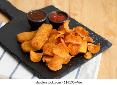 Top View Homemade Organic Baked Fried Sweet Potatoes Chips And Fish Fingers Served Home Made Tomato Sauce And Barbecue Sauce On Black Slate Plate, Healthy Snack For Family Concept