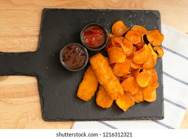 Top View Homemade Organic Baked Fried Sweet Potatoes Chips And Fish Fingers Served Home Made Tomato Sauce And Barbecue Sauce On Black Slate Plate, Healthy Snack For Family Concept