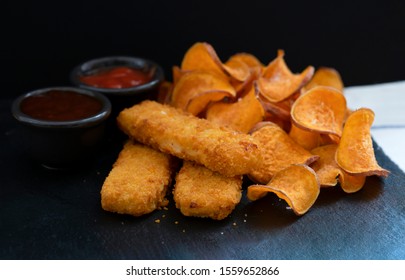 Top View Homemade Organic Baked Fried Sweet Potatoes Chips And Fish Fingers Served Home Made Tomato Sauce And Barbecue Sauce On Black Slate Plate, Healthy Snack For Family Concept