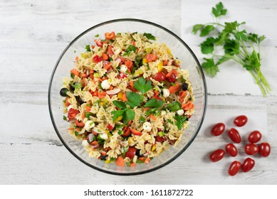 Top View Of Homemade Pasta Salad With Fresh Vegetables And Herbs On A White Wood Background