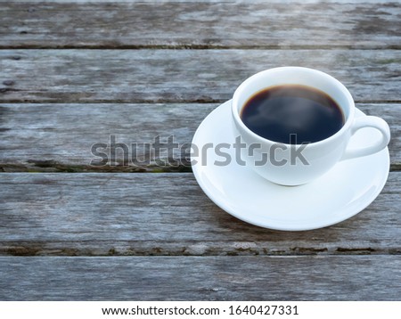Top view of a hot aromatic brewed mug of black organic coffee on rustic and weathered wood palnk background.
