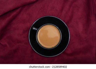 Top View Of Hot Black Tea Cup On Red Bedsheet.