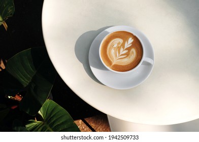 Top view of Hot coffee latte and heart shaped latte art in a white glass on a white background