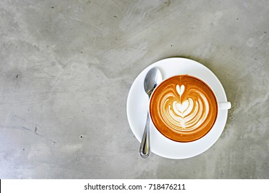 Top view of hot coffee latte with latte art,A cup of coffee , cappuccino art ,Cappuccino with beautiful foam and spoon in white cup ,Copy space.