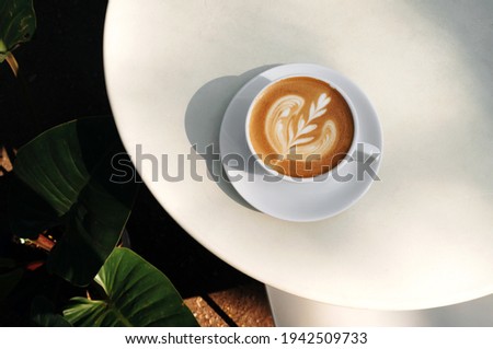 Top view of Hot coffee latte and heart shaped latte art in a white glass on a white background