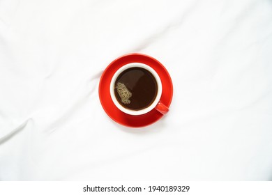 Top View Of Hot Coffee In A Red Ceramic Mug On White Tablecloths With Morning Light.