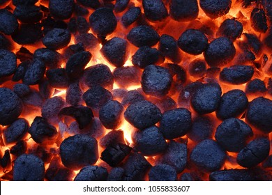 Top View Of Hot Flaming Charcoal Briquettes Glowing In The BBQ Grill Pit. Abstract Red Black Background, Texture Or Wallpaper. Burning Coals For Cooking Barbecue Food. Close Up.