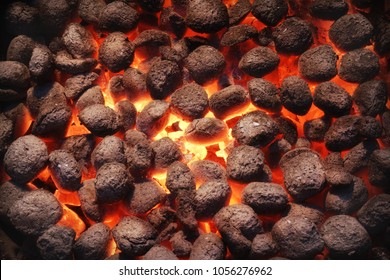 Top View Of Hot Flaming Charcoal Briquettes Glowing In The BBQ Grill Pit. Abstract Red Black Background, Texture Or Wallpaper. Burning Coals For Cooking Barbecue Food. Close Up.