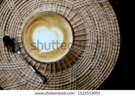 Top view of Hot Latte Art fresh coffee in a cup with heart milk foam, on wooden table background. Drink concept. dark tone.