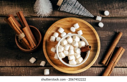 Top View  Hot Spicy Drink With Marshmallows On Wooden Background. Cinnamon Sticks And  Small Christmas Tree  Mess On Table.