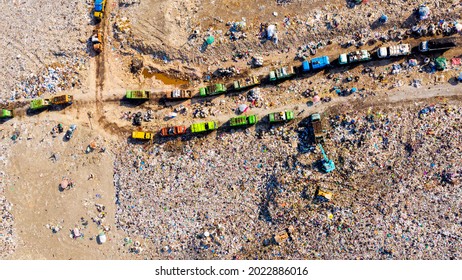 Top view of A Huge Waste, garbage, dump, rubbish landfill. A landfill compactor, group of workers sort out the garbage in the landfill. Trash trucks dump waste polluting products.
