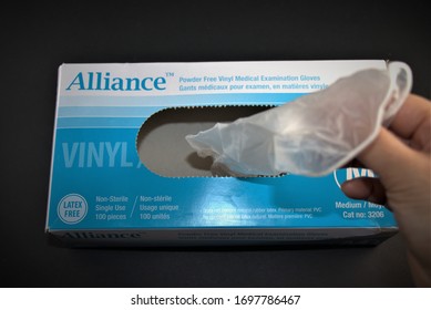 Top View Of Human Hand Pulled Last Piece Of Medical Examination Glove From A Box. Close Up Photo Isolated On Black Background. Shortage Of Personal Protective Equipment (PPE) Supplies. April 07,2020