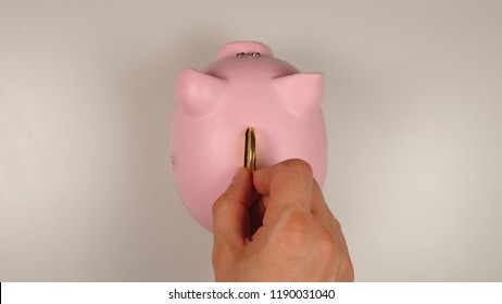 TOP VIEW: Human Hand Throws A Coin Into Pink Pig Money Box