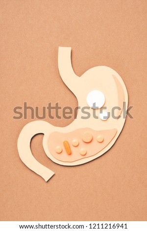 top view of human stomach with different pills on beige
