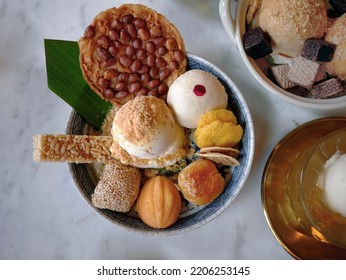 Top view of ice cream, fried peanut cookie, mini castella, sesame bar, Soft Flour Cake, peanut snack, Chinese pastry, bean cake, Thai fusion menu serving in blue chinaware on the marble table