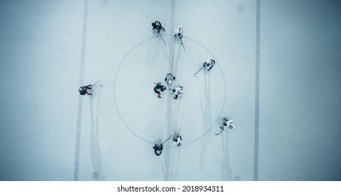 Top View Ice Hockey Rink Arena Game Start: Two Players Face off, Sticks Ready, Referee Ready to Drop the Puck. Intense Game Wide of Competition. Aerial Shot
