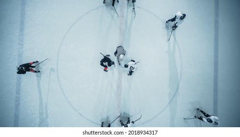 Top View Ice Hockey Rink Arena Game Start: Two Players Face Off, Sticks Ready, Referee Ready To Drop The Puck. Intense Game Wide Of Competition. Aerial Drone Shot