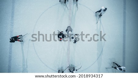 Top View Ice Hockey Rink Arena Game Start: Two Players Face off, Sticks Ready, Referee Ready to Drop the Puck. Intense Game Wide of Competition. Aerial Drone Shot