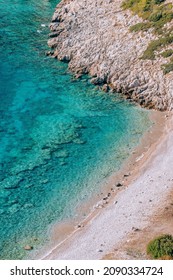 Top View Of The Idyllic Pebble Beach With Turquoise Water. Perfect Summer Holiday Escape Destination Spot. Landscape Of The Wild Beach Without People At Mediterranean Sea