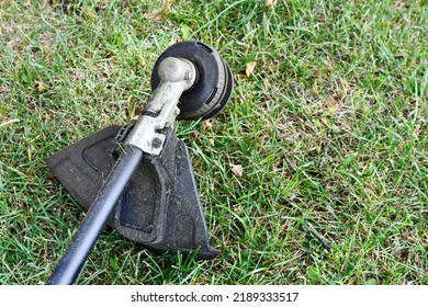 A Top View Image Of A Black And Yellow Weed Whacker On Green Grass. 