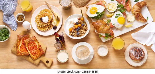 Top view image of brunch menu on wooden table. Healthy sunday breakfast with croissants, waffles, granola and sandwiches. Flatlay with tasty food