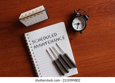 Top view image of calendar, alarm clock, screwdriver and book with text SCHEDULED MAINTENANCE. - Powered by Shutterstock