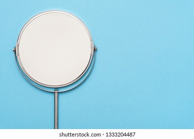 Top View Image Of Circle Hand Mirror On Blue Background. Flat Lay.