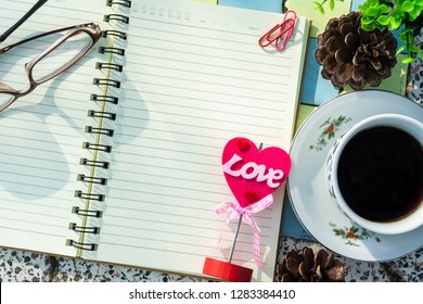 Top view image of empty notebook,spectacles and cup of coffee on Marble floor background. Love concept with heart desktop,Valentine's Day.