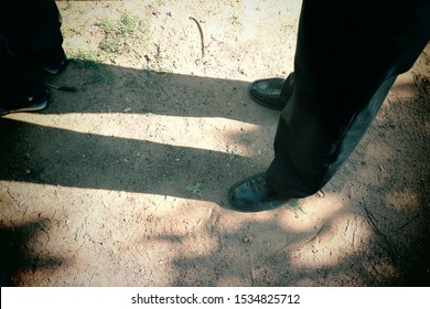 Top view image, light and shadow. Men wearing black shoes stand on the ground during the day time.  Copy space