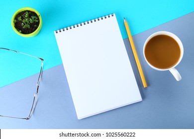 Top view image of open notebook with blank pages and coffee on blue background, ready for adding or mock up. Still life, business, office supplies or education concept. Notepad. Note paper.