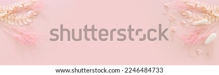 Top view image of pink dry flowers over pastel background .Flat lay