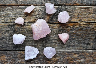 A top view image of rose quartz crystals shaped in a circular energy healing grid on an old wooden table top. 
