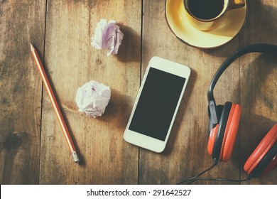 top view image of smartphone with blank screen headphones and coffee cup. room for text . faded style image
