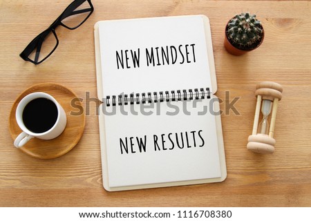 top view image of table with open notebook and the text new mindset new results. success and personal development concept