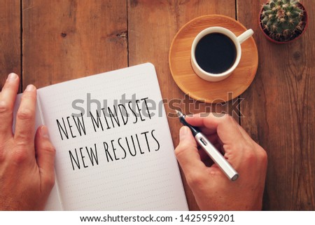 top view image of table with open notebook and the text new mindset new results. success and personal development concept