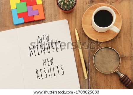 top view image of table with open notebook and the text new mindset new results. success and personal development concept