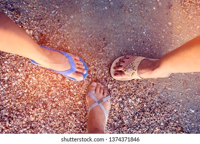 Top view image of three different pair of slippers of Asian woman standing in  a circle at the sandy beach, tourist friend standing on the beach with shell cracked