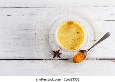 Top view image of turmeric latte over white wooden table with copyspace