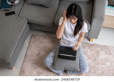 Top view image of a young Asian woman sits on a carpet in the living room and uses her digital tablet. a digital tablet with a wireless keyboard. domestic life and wireless technology concepts - Powered by Shutterstock