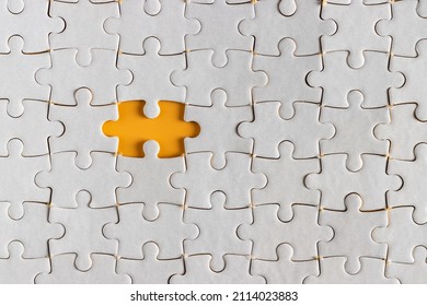 Top view of incomplete white jigsaw puzzle. without last piece of puzzle. revealing orange or yellow background. 